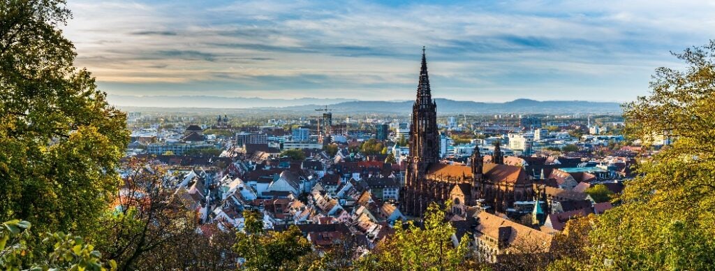 Germany, XXL panorama of city freiburg im breisgau skyline with cathedral muenster in old town in warm sunset light in romantic autumn season, aerial view above cityscape